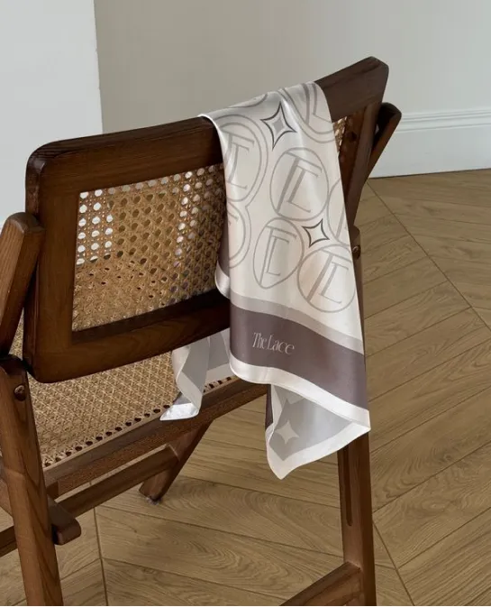 Monogrammed silk scarf draped over a cane-back wooden chair