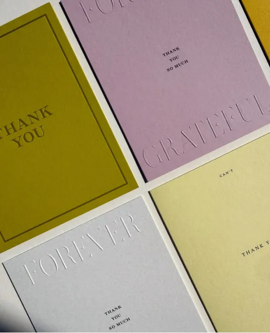 Assorted thank-you cards in olive, lilac, gray, and yellow with embossed lettering