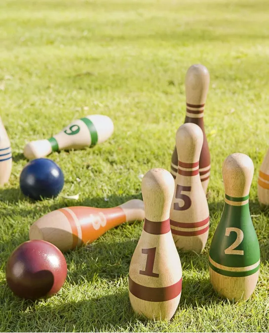 Numbered wooden lawn bowling pins and balls on grass