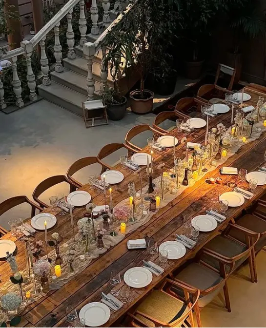 Overhead view of a long candlelit communal dinner table set in a courtyard