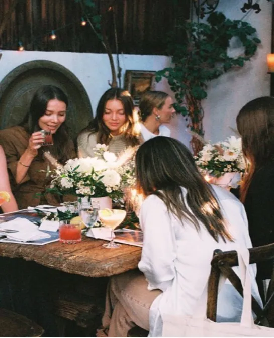 Friends gathered around an evening dinner table with white florals and cocktails